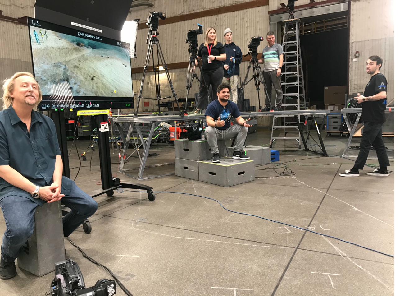 A performer in a mocap suit holding a Moana doll — a typical Friday night on Avatar