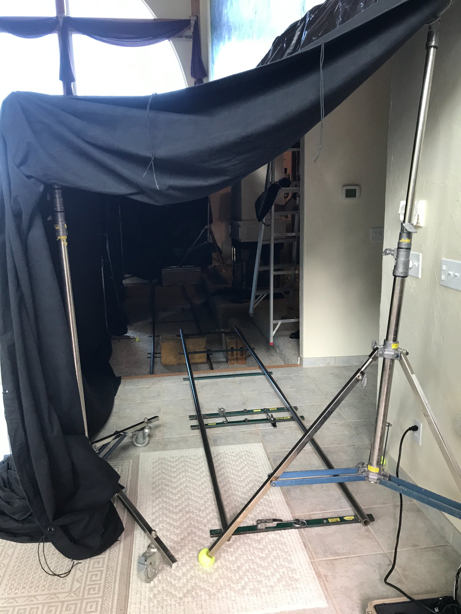 Wide view of the VRBO mansion living room with the massive blackout tent constructed on the right side — lake visible through the arched window