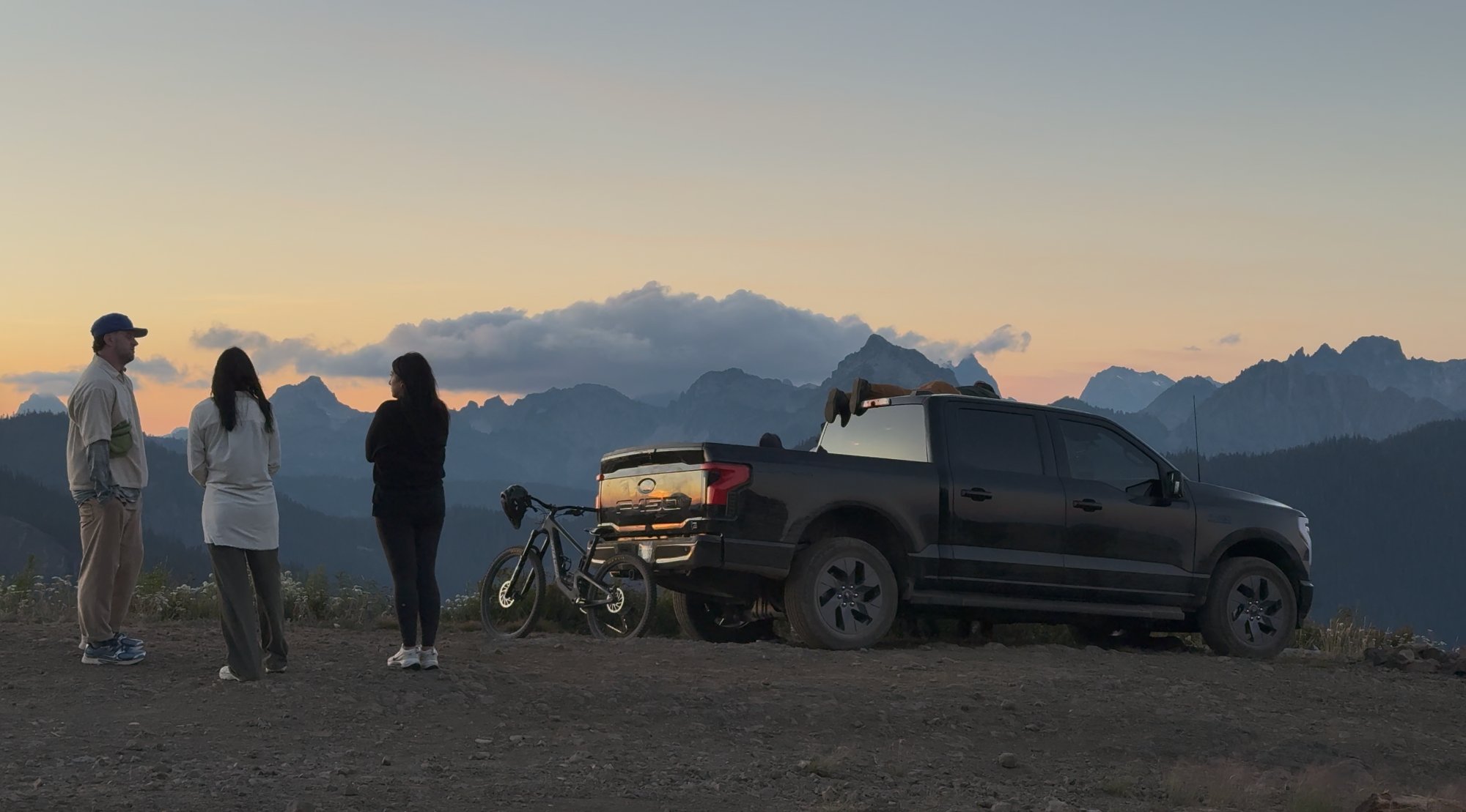 The F-150 Lightning at sunset with the crew silhouetted against the Cascade mountain range