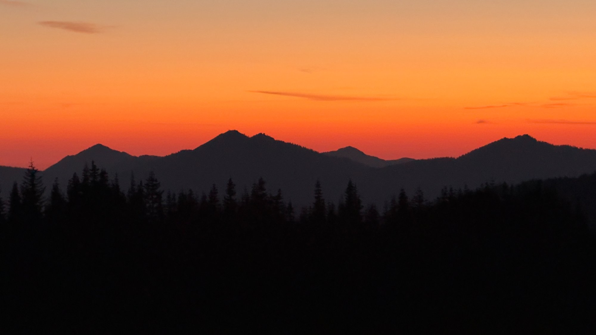 Cascade mountain silhouettes at sunset — deep orange sky over Washington state