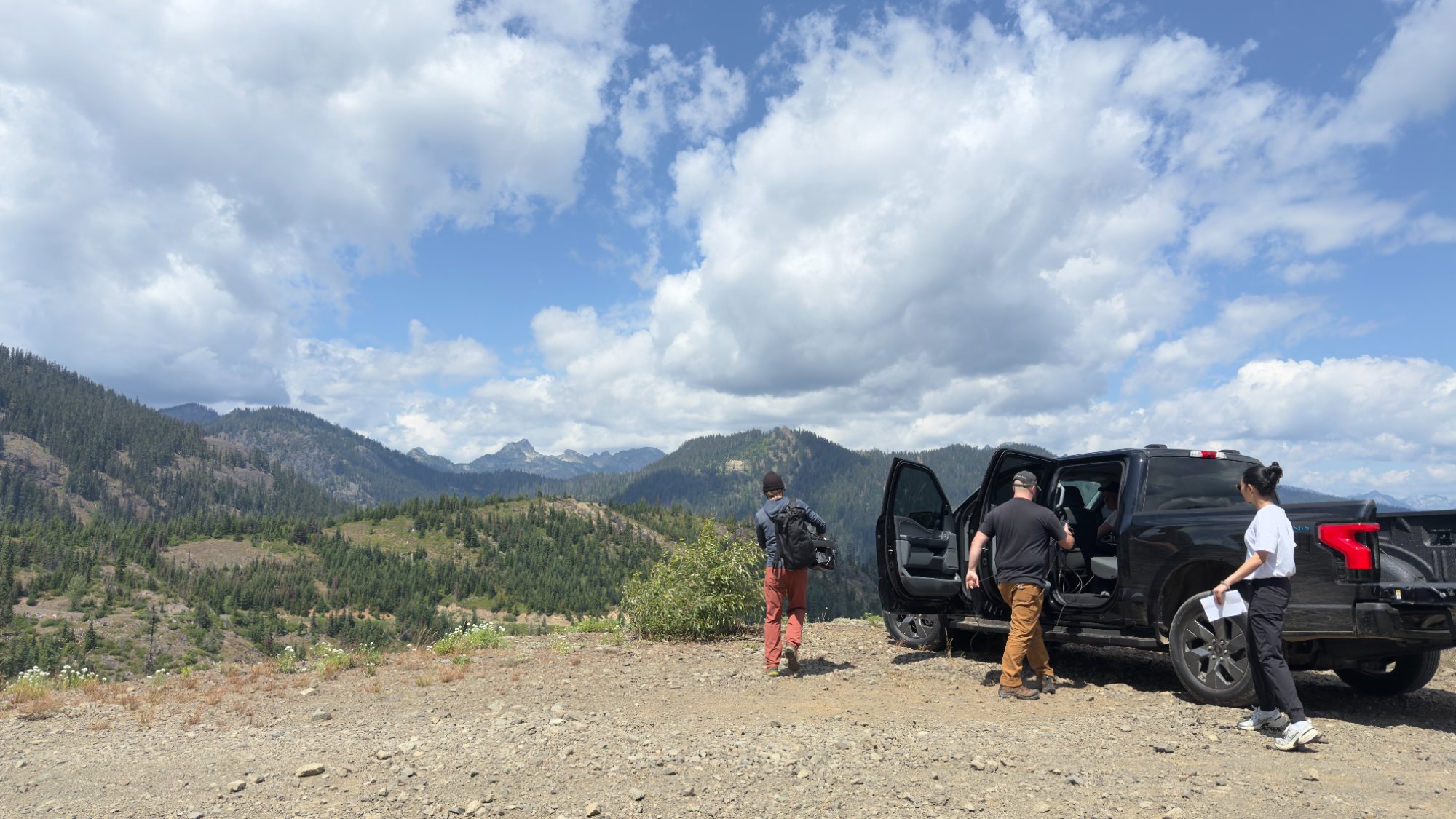 The small crew with the F-150 Lightning on a dirt ridge overlooking the Cascades