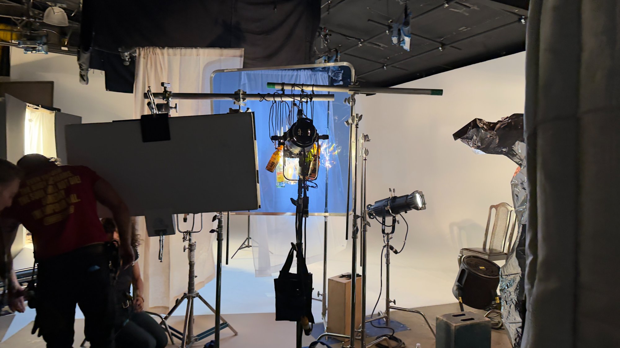 Empty bottles and colored gel hung in front of lights on a white cyc stage — the breathing light setup